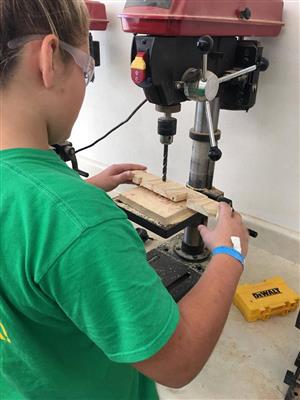 Student working on drill press during woodshop 