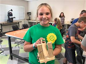 Student showing off catapult made in woodshop 